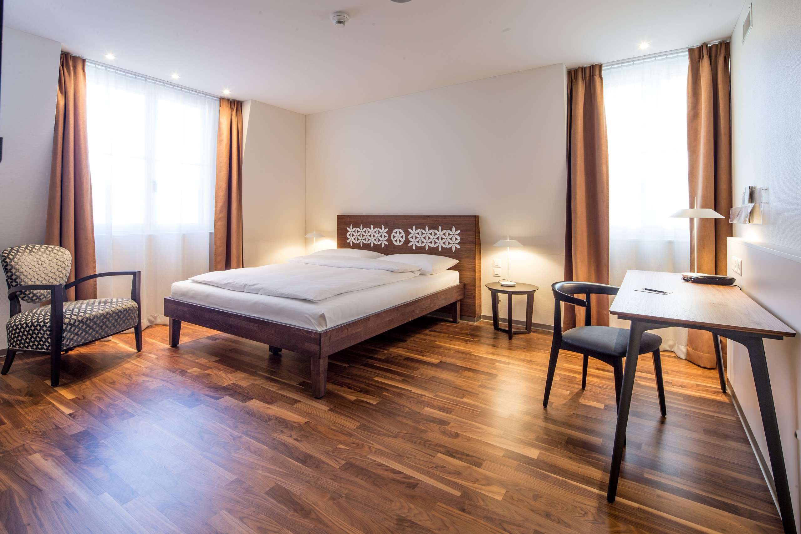 Helles modernes Schlafzimmer mit Doppelbett, Schreibtisch, Stuhl und Holzfußboden.